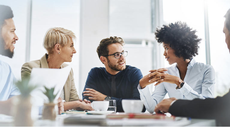 Group of employees sitting around a conference table having a discussion.
