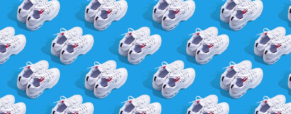 pairs of white athletic sneakers resting against a blue background