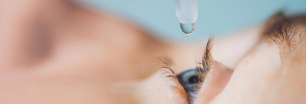 closeup of a person putting an eye drop in their eye