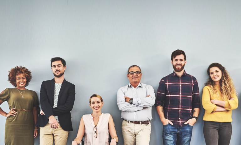 A group of diverse individuals standing in front of a blank wall.