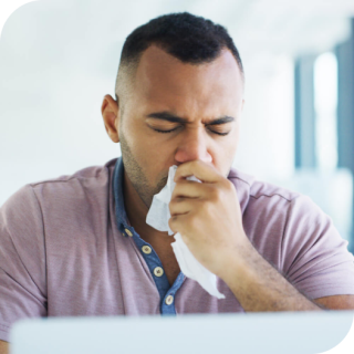 man blowing nose into a tissue
